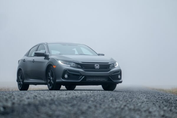 A sleek silver car parked on a foggy road, showcasing its elegance.